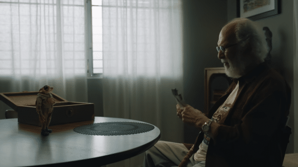 An old man conversating with a talking toad showing him pictures.
